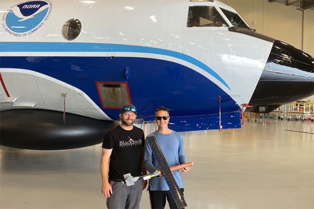 Researchers holding drone in front of plane